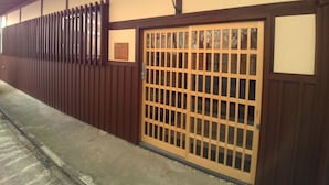 A traditional Japanese building with a wooden fence, a sliding gate, and a concrete pathway.
