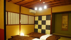 A traditional Japanese-style room with tatami flooring, a checkered wall, and a bed with brown bedding.