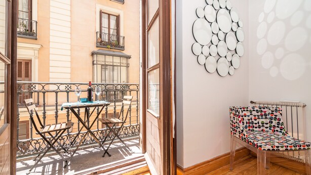 A balcony with a table and chairs, a wall with circular mirrors, and a patterned chair. - MADRID-SOL-GATE PLAZA MAYOR, New Apartment, Comodo, modern design. (Madrid)
