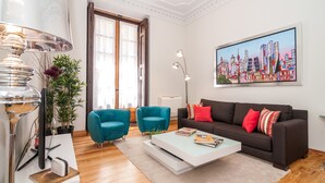 A modern living room with a sofa, two armchairs, a coffee table, and a cityscape painting on the wall. - MADRID-SOL-GATE PLAZA MAYOR, New Apartment, Comodo, modern design. (Madrid)