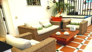 Ein gemütlicher Wohnbereich mit Korbmöbeln, einem Couchtisch und einem Blumentopf.