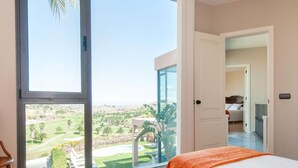 A hotel room with a large sliding glass door leading to a private outdoor area with a view of a golf course.