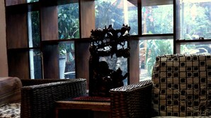 A room with a large window, wicker furniture, and a patterned tablecloth.