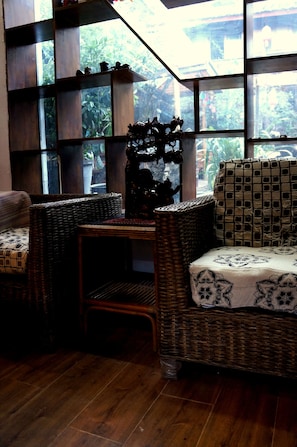 A room with a large window, wicker furniture, and a patterned tablecloth. - Delamu Inn (Lijiang)