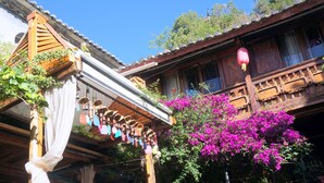 A traditional wooden building with a balcony, potted plants, and hanging decorations.