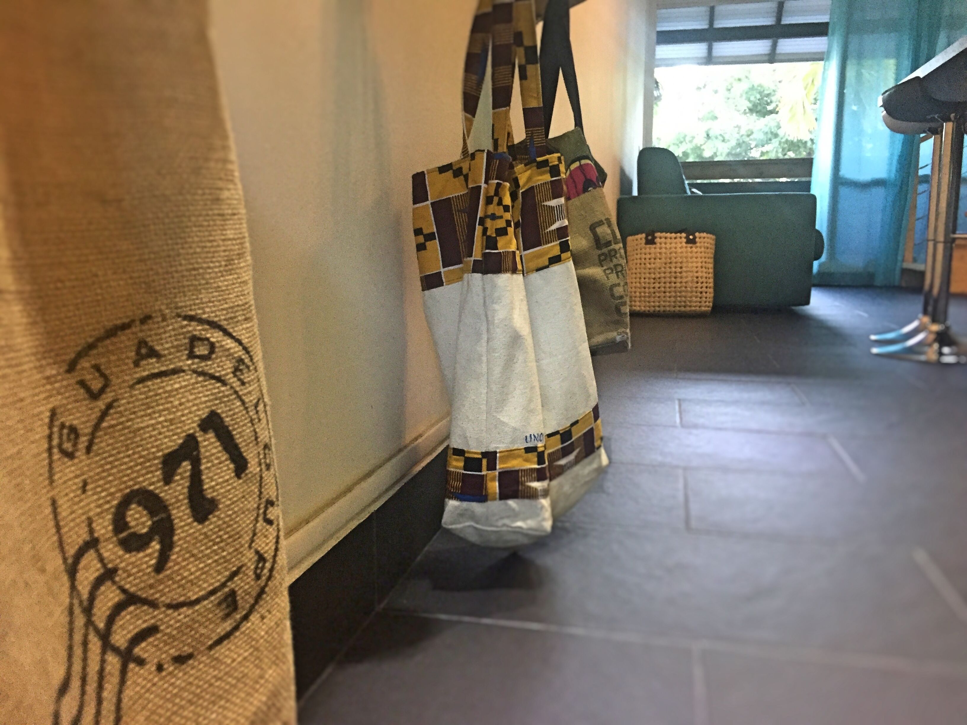 A hallway with a patterned wall, a woven bag hanging, and a woven basket on the floor.