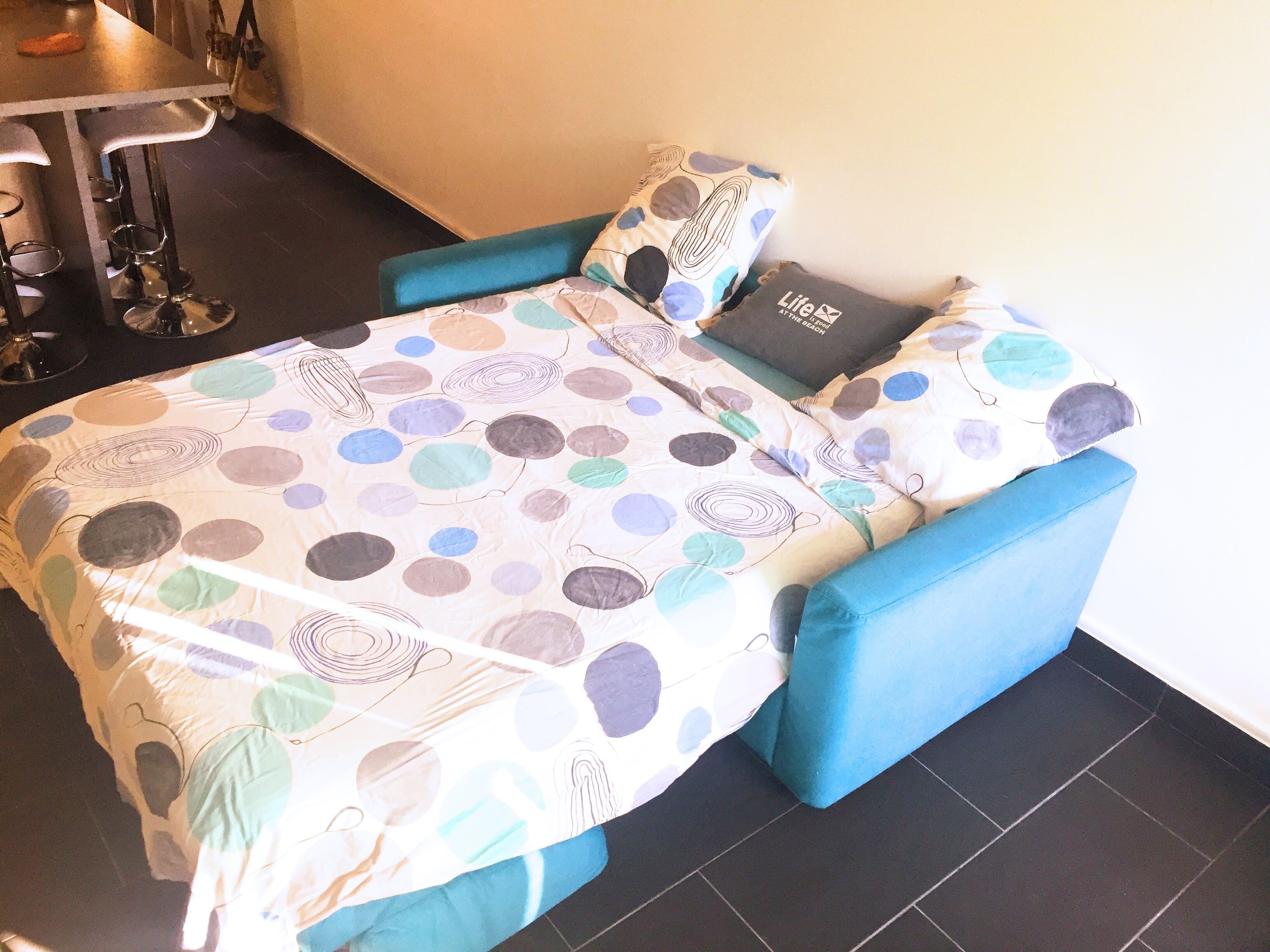 A small, cozy room with a bed, a chair, and a table.