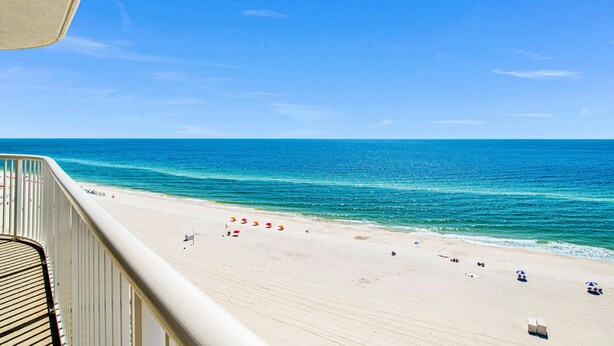 A beach view from a balcony with a railing, a sandy beach, and the ocean. - Beachfront 2BR @ Tradewinds • Sleeps 6 • Stunning Gulf Views • Pool Access (Orange Beach)
