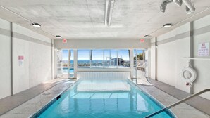 An indoor swimming pool with clear glass walls, exit signs, and a no smoking sign. - Beachfront 2BR @ Tradewinds • Sleeps 6 • Stunning Gulf Views • Pool Access (Orange Beach)
