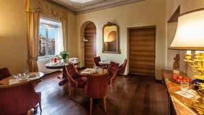 A dining area with a round table, red upholstered chairs, and a chandelier. - Prestigious Apartment Piazza Navona - Campo de' Fiori - Holiday in Rome (Roma)
