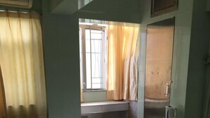 A dormitory room with two single beds, a desk, a chair, and a window with curtains. - Capital Guesthouse (Kowloon)