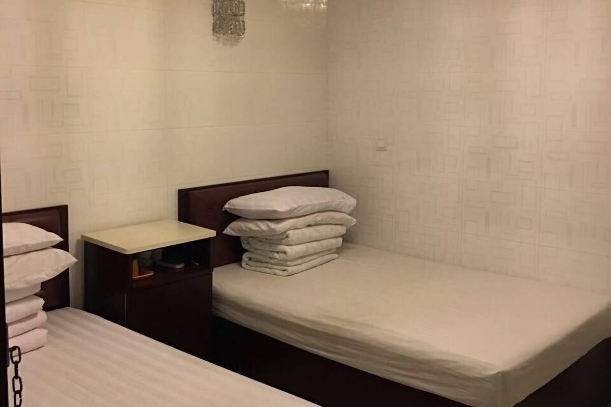 A hotel room with a bed, a bedside table, and a nightstand.