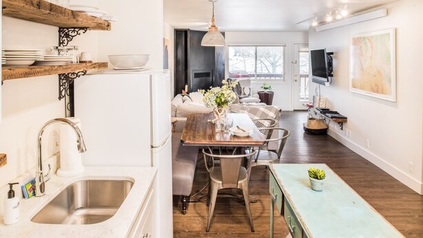 A modern kitchen with a wooden dining table, white cabinets, and a built-in oven. - Outpost: Pitchfork 2303 - Close to Snow King Mtn! (Jackson)