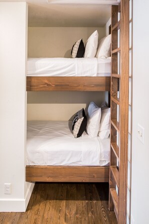 A bunk bed with white bedding and wooden headboard.