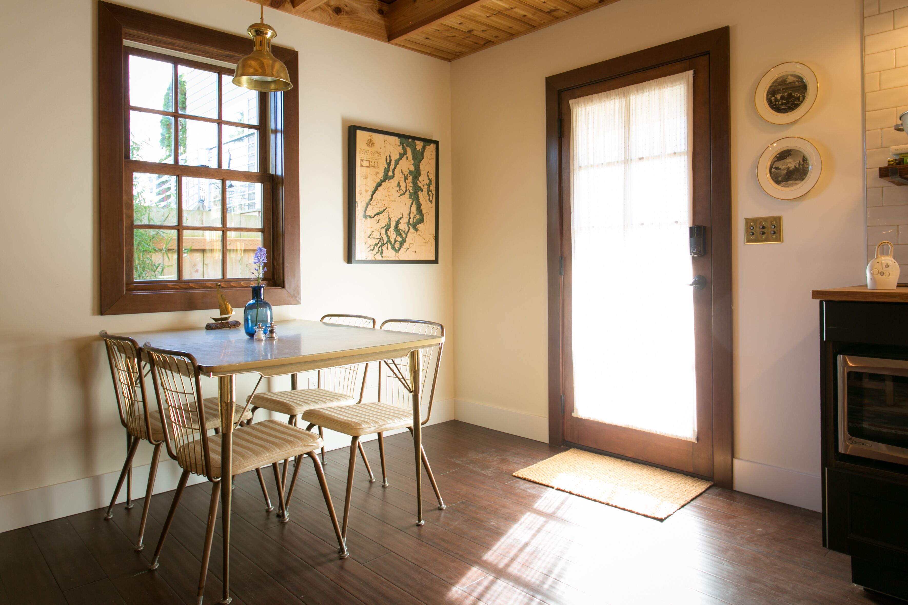 A dining area with a wooden table and chairs, a map on the wall, and a door leading to another room.