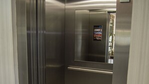Un ascensor con paredes metálicas, un panel de control y una pantalla digital.