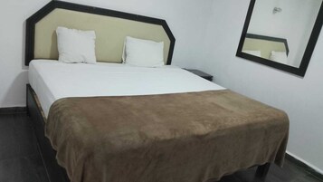 Una cama con cabecera, dos almohadas y una manta marrón.