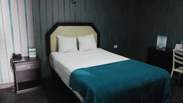 Una habitación de hotel con cama, mesita de noche, escritorio y silla.