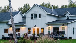 A two-story white house with a covered porch and outdoor seating area. - Snowgoose Pond Bed & Breakfast (Palmer)