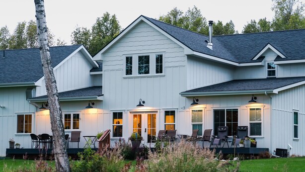 A two-story white house with a covered porch and outdoor seating area. - Snowgoose Pond Bed & Breakfast (Palmer)