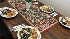 A dining table set with plates of food, a vase of tulips, and a decorative runner. - Snowgoose Pond Bed & Breakfast (Palmer)