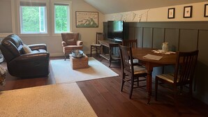 A cozy living room with a fireplace, a dining area, and a television. - Snowgoose Pond Bed & Breakfast (Palmer)