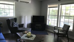 Una sala de estar con televisor, dos sillones, un sofá y una mesa de centro.
