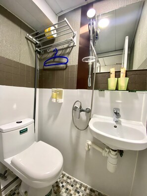 A bathroom with a toilet, sink, shower, and a towel rack. - Hong Kong Hostel (Kowloon)