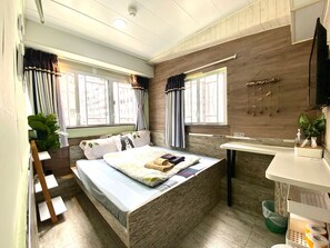A bedroom with a bed, a bedside table, a window with curtains, a plant, and a wooden wall. - Hong Kong Hostel (Kowloon)