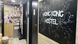 A hostel interior with a reception desk, a bulletin board, and a wall with 'Hong Kong Hostel' written on it. - Hong Kong Hostel (Kowloon)