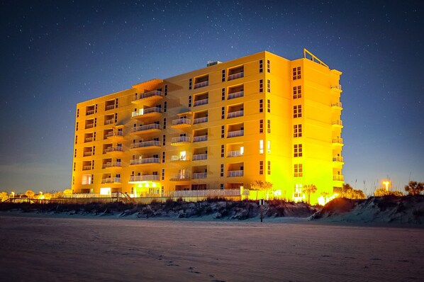 Un hôtel à plusieurs étages, doté de balcons, situé près d’une plage.