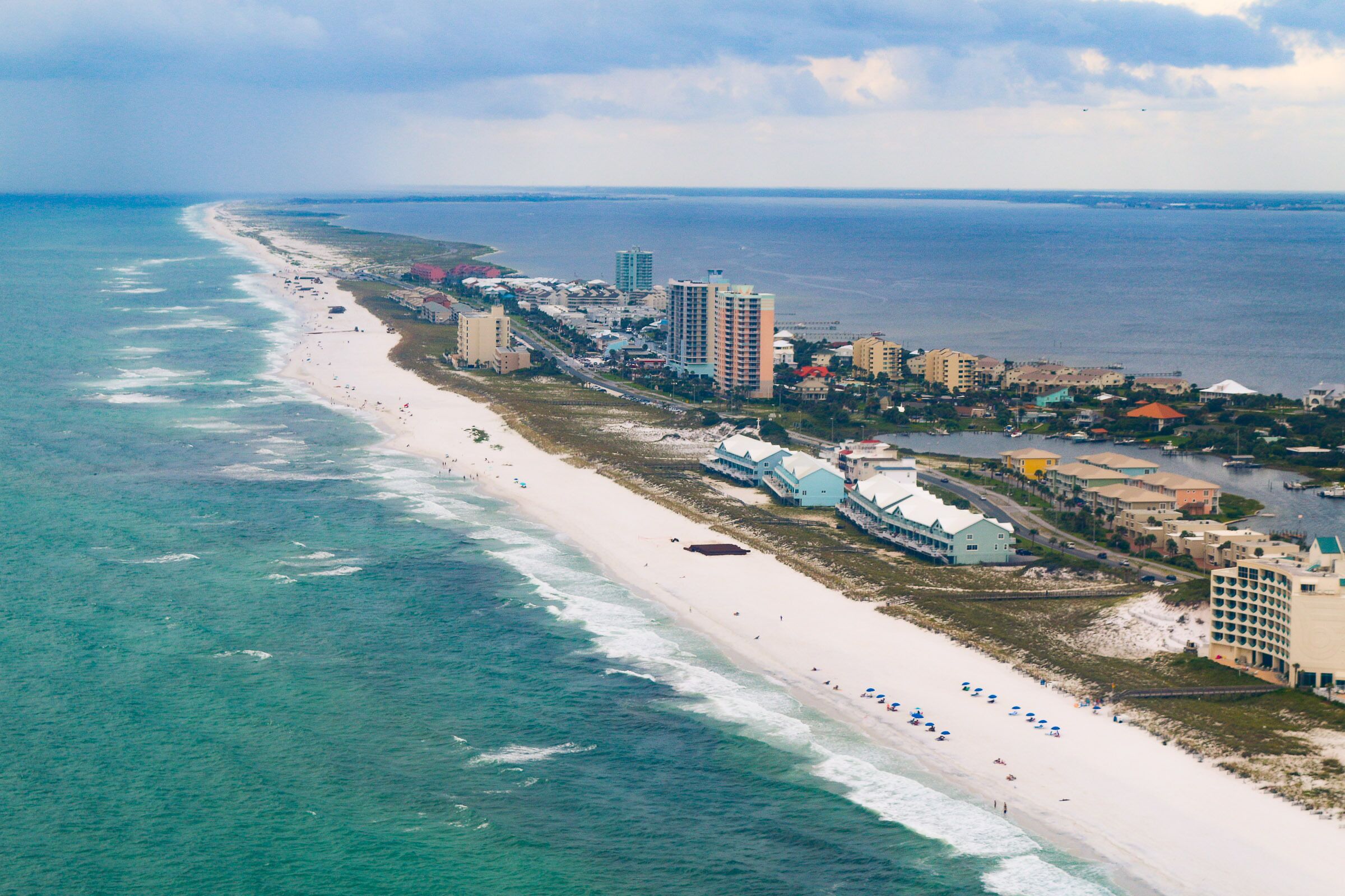 Luchtbeeld van een kustgebied met strand, oceaan en een rij hotels.
