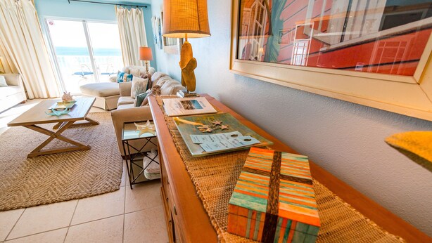 A cozy living room with a sofa, a coffee table, and a lamp. There is a view of the ocean through a glass door. - Spectacular Beach Front Views!  Free Lazy Days Beach Chairs & Umbrella Included! (Pensacola Beach)
