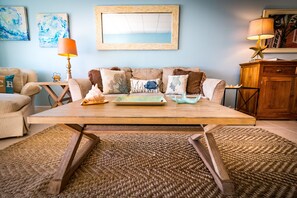 Ein Wohnzimmer mit Couch, Holz-Couchtisch, Kissen mit Muster, einer Lampe in Form eines Seesterns und einem gerahmten Bild an der Wand.