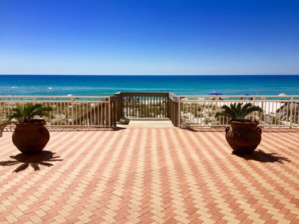 A paved deck with a view of the beach and ocean.