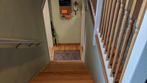 Un escalier en bois avec une rampe, un panneau d’accueil et un petit tapis au bas de l’escalier.