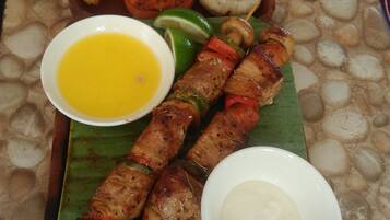 Un repas composé de brochettes de viande grillée, de frites, d’un bol de soupe et d’une petite portion de sauce.
