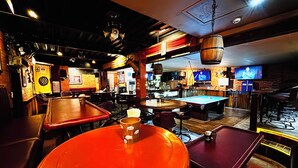 A bar with pool tables, a dartboard, and a television screen. - Mango's Beachfront Resort (Olongapo)