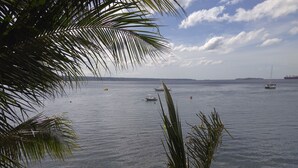 A view of a calm sea with several boats, a sandy beach, and a distant island. - Mango's Beachfront Resort (Olongapo)