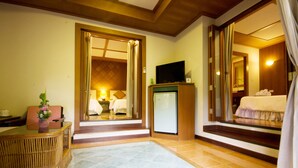 Habitación de hotel con mostrador de recepción, televisión, cama y baño visible a través de una puerta abierta.