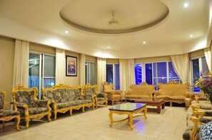 A spacious living room with ornate golden furniture, large windows with curtains, and a ceiling fan. - Blue Lagoon Pool Villa (Pattaya)