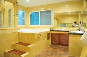 A bathroom with a large bathtub, a sink, and a mirror. - Blue Lagoon Pool Villa (Pattaya)