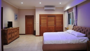 A bedroom with a bed, a dresser, a wardrobe, and an air conditioning unit. - Blue Lagoon Pool Villa (Pattaya)