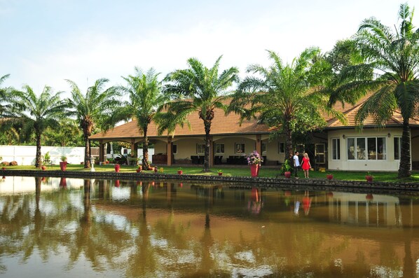 A hotel with a pool, palm trees, and a covered patio area. - Blue Lagoon Pool Villa (Pattaya)