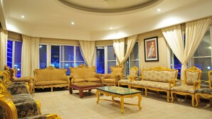 A luxurious living room with ornate golden furniture, large windows with curtains, and a ceiling fan. - Blue Lagoon Pool Villa (Pattaya)
