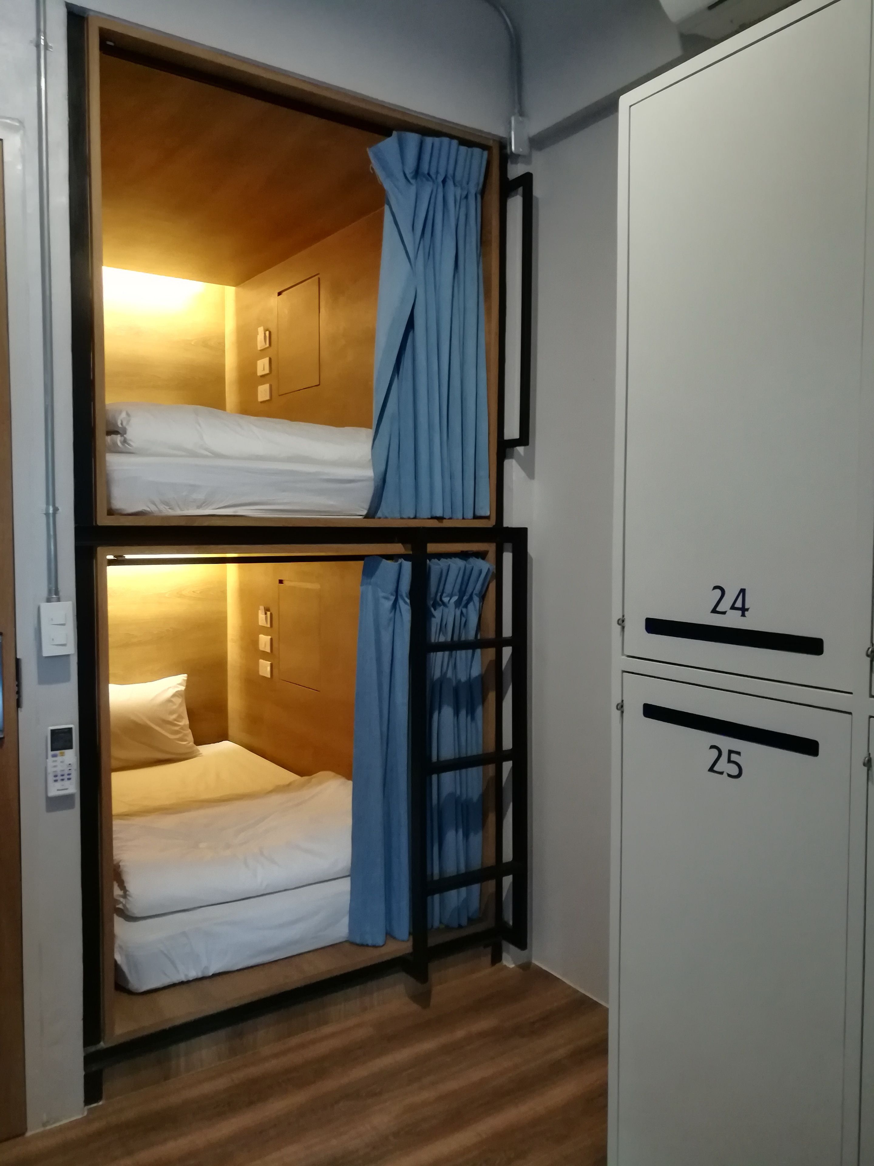 Ein Schlafraum mit Etagenbetten, einem Bedienfeld, Holzwänden und einem Schrank mit nummerierten Fächern.