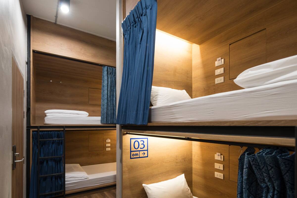 A bunk bed room with wooden walls, a blue curtain, and a sign indicating room number 03.