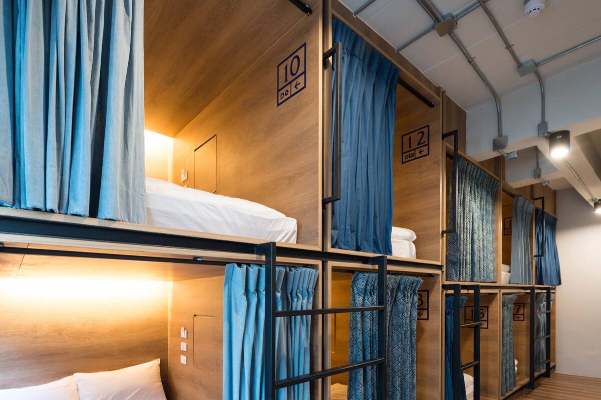 A dormitory-style room with bunk beds, each with a number sign indicating the room number.