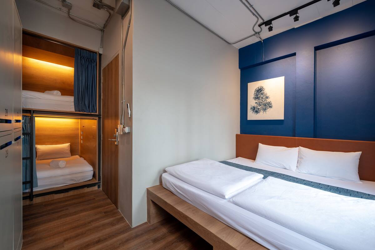A hotel room with a bed, a bench, a wardrobe, and a wall-mounted artwork.