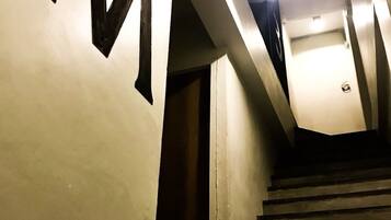 Una escalera con barandilla e iluminación superior.